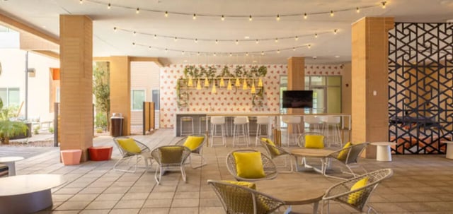 Paved outdoor seating area with yellow cushions and bar living room at Apollo Tempe in Tempe Student Accommodation