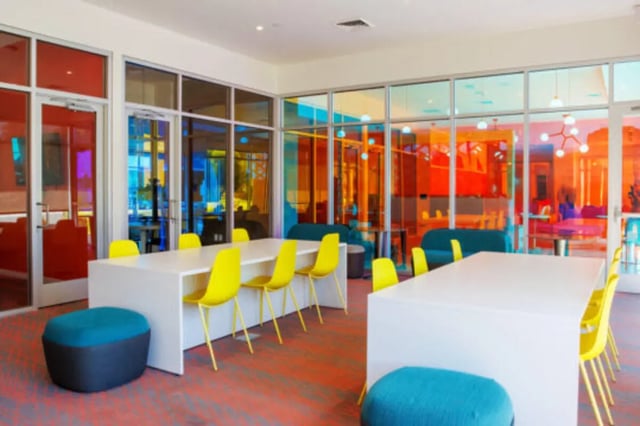White tables yellow chairs blue ottomans common area at Apollo Tempe in Tempe Student Accommodation