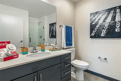 Modern grey vanity toilet towels artwork bathroom at Here Kansas in Lawrence Student Accommodation