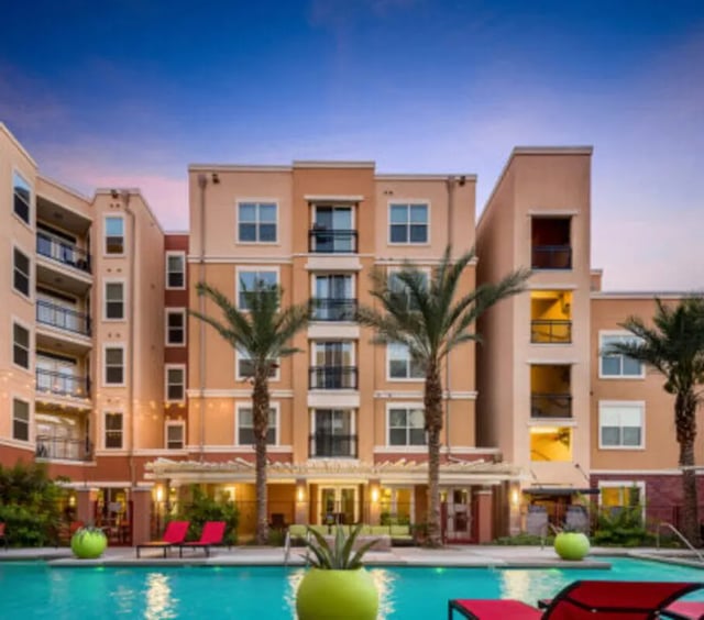 Pool lounge chairs palm trees apartment building exterior at The District on 5th in Tucson Student Accommodation