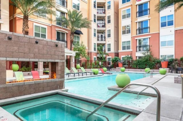 Pool with lounge chairs and fireplace exterior at The District on 5th in Tucson Student Accommodation