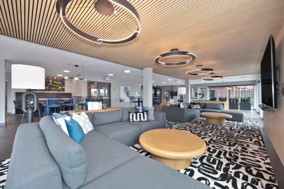 Large grey sectional sofa round wooden coffee table living room at ANOVA Aggie Square in Sacramento Student Accommodation