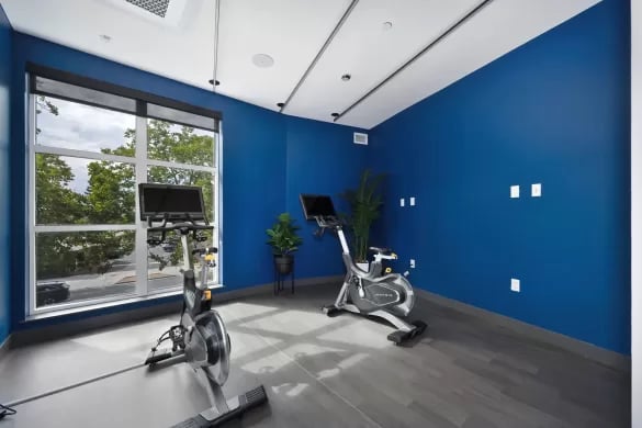 Two exercise bikes on blue walls fitness room at ANOVA Aggie Square in Sacramento Student Accommodation