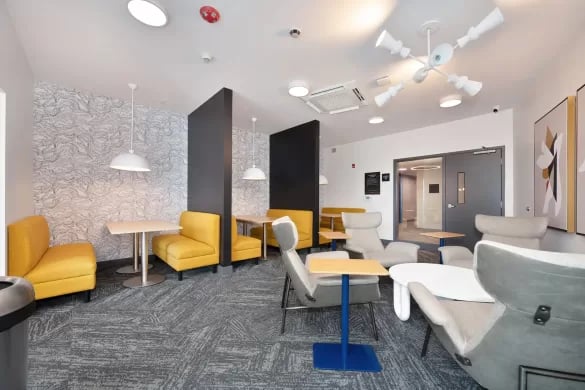 Modern communal lounge with yellow seating and tables at ANOVA Aggie Square in Sacramento Student Accommodation