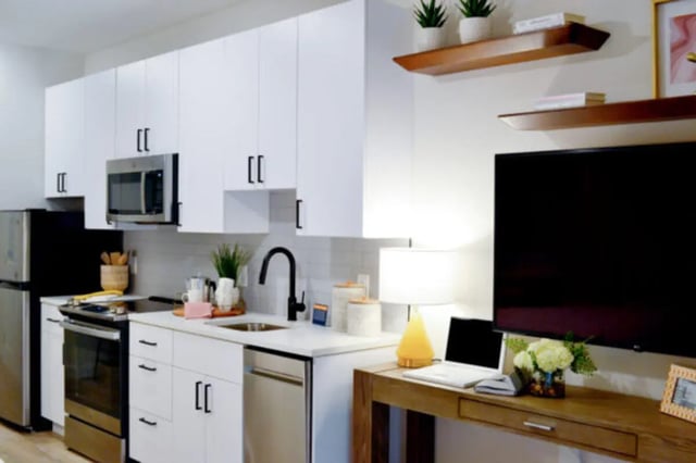 Modern kitchen with stainless steel appliances and living area. at ANOVA uCity Square in Philadelphia Student Accommodation