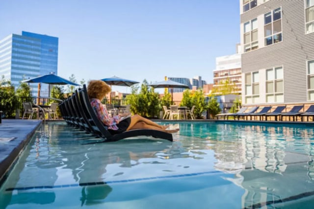 Woman on lounger by pool near buildings exterior at ANOVA uCity Square in Philadelphia Student Accommodation