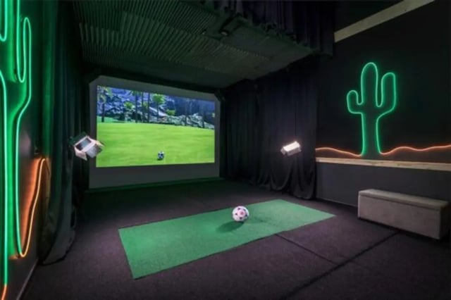 Golf simulator with screen soccer ball and neon cactus playing area at The District on Apache in Tempe Student Accommodation