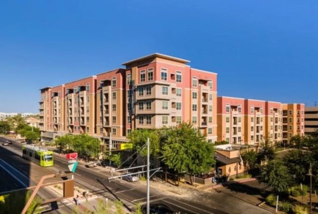 Apartment building with tram and trees exterior at The District on Apache in Tempe Student Accommodation