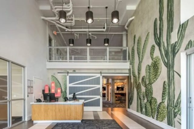 Reception desk with cactus mural and barn door lobby at The District on Apache in Tempe Student Accommodation