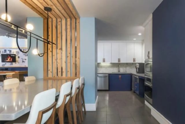 Long table with chairs and kitchen area Kitchen at The District on Apache in Tempe Student Accommodation