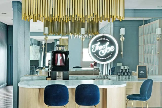 Coffee bar with navy chairs and neon sign lounge at The Kristi in Corpus Christi Student Accommodation