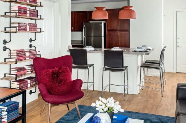 Bookshelf armchair counter stools refrigerator kitchen area at The Kristi in Corpus Christi Student Accommodation