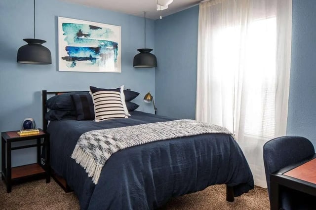 Bed with blue bedding bedside table abstract art Bedroom at The Kristi in Corpus Christi Student Accommodation