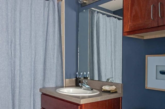 Sink mirror shower curtain toothbrushes and cabinets bathroom at The Kristi in Corpus Christi Student Accommodation