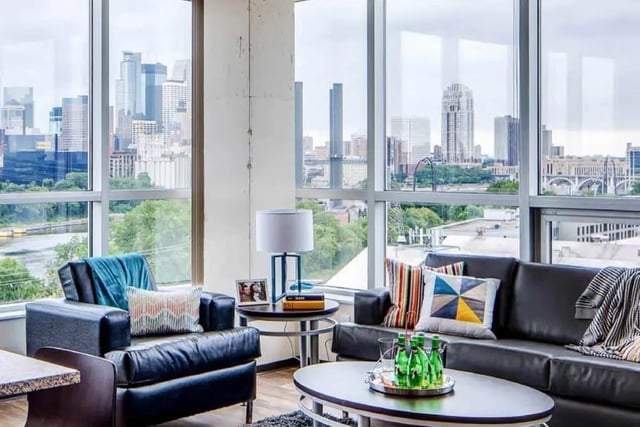 Black leather couch armchairs table lamp cityscape living room at The Bridges Dinkytown in Minneapolis Student Accommodation
