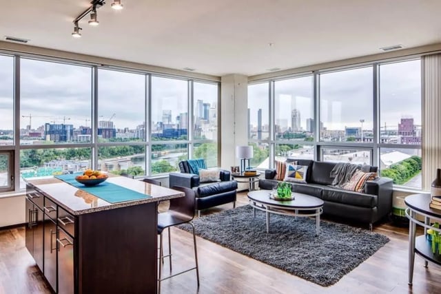 Kitchen island black sofas large windows living room at The Bridges Dinkytown in Minneapolis Student Accommodation
