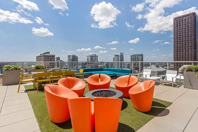 Orange chairs fire pit blue seating yellow tables exterior at Arc at Old Colony in Chicago Student Accommodation