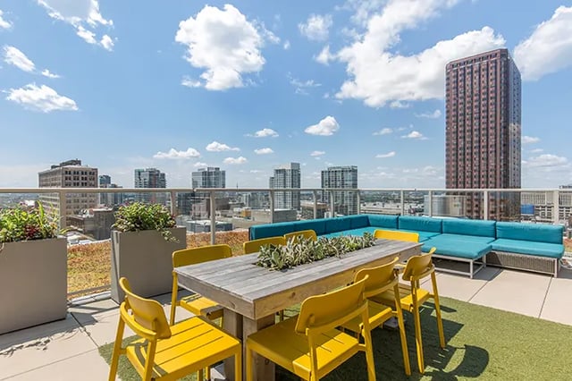 Rooftop dining area with blue sectional and yellow chairs exterior at Arc at Old Colony in Chicago Student Accommodation