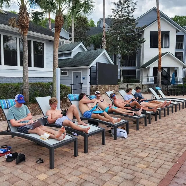 Students lounging on chairs by buildings exterior at Hideaway Gainesville in Gainesville Student Accommodation