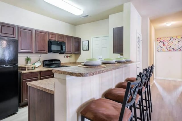 Dark wood cabinets black fridge and microwave kitchen with bar stools kitchen at High View in San Antonio Student Accommodation