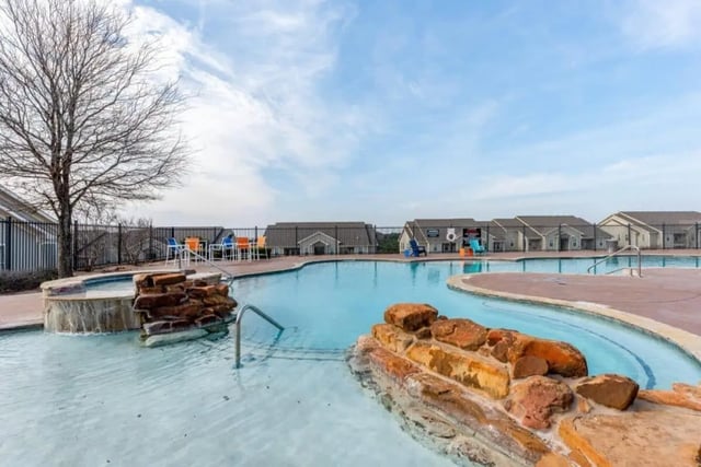 Pool with rock waterfall and lounge chairs exterior at High View in San Antonio Student Accommodation