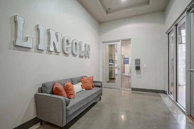 Gray couch with pillows and Lincoln sign entryway at Academy in Lincoln Student Accommodation