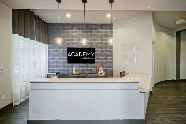 Modern reception desk with patterned wall and TV reception area at Academy in Lincoln Student Accommodation