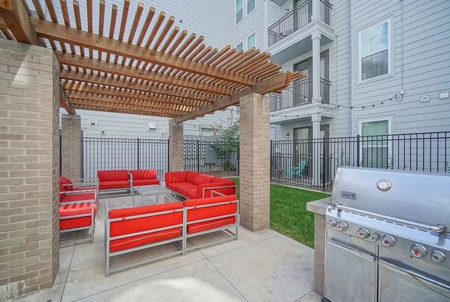 Red couches under pergola with grill outdoor area at Academy in Lincoln Student Accommodation