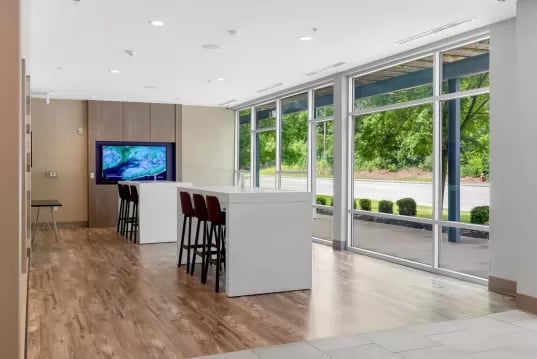 TV bar stools white tables large windows living room at GrandMarc Clemson in Clemson Student Accommodation