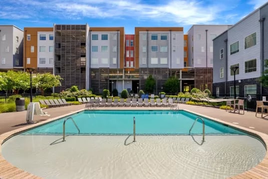 Swimming pool with lounge chairs and apartment building exterior at GrandMarc Clemson in Clemson Student Accommodation