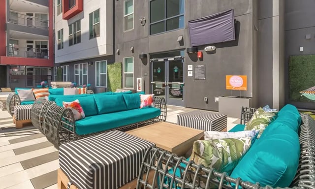 Outdoor lounge with teal sofas striped ottomans exterior at Academy65 in Sacramento Student Accommodation