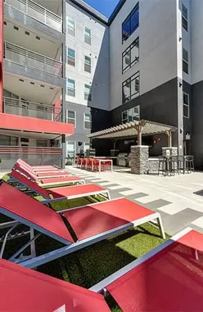 Red loungers and outdoor kitchen patio area exterior at Academy65 in Sacramento Student Accommodation