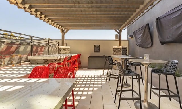 Pergola seating area with red and black chairs exterior at Academy65 in Sacramento Student Accommodation