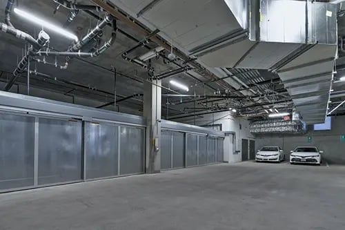 Parking garage with cars and sliding doors exterior at IDENTITY Logan Park in Berkeley Student Accommodation