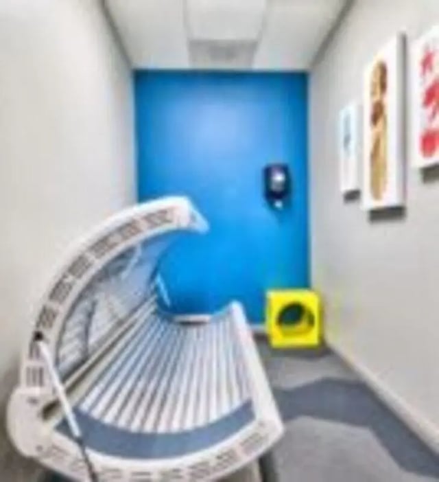 Tanning bed on blue wall with art Tanning room at GrandMarc at University Village in Riverside Student Accommodation
