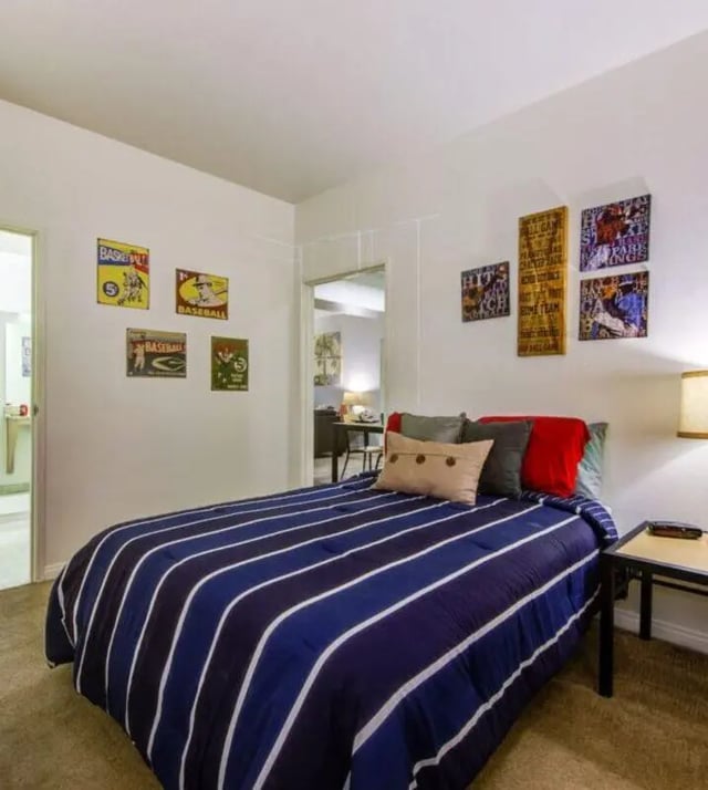 Bed with striped comforter and wall art bedroom at GrandMarc at University Village in Riverside Student Accommodation