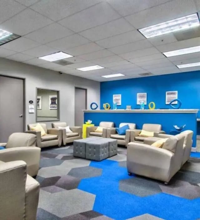 Lounge with chairs gray ottoman blue wall living room at GrandMarc at University Village in Riverside Student Accommodation