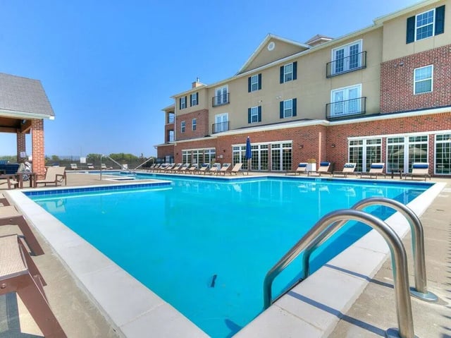 Pool with lounge chairs building exterior outdoor area at The Grove Apartments Ames in Ames Student Accommodation