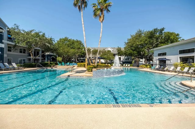 Pool with lounge chairs and palm trees exterior at The Verge in Orlando Student Accommodation