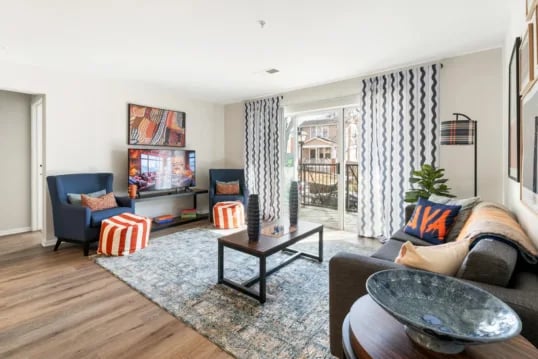 Blue chairs tv striped ottomans coffee table living room at Grandmarc at The Corner in Charlottesville Student Accommodation
