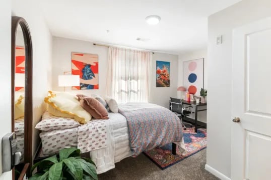 Bed desk plant artwork colorful rug bedroom at Grandmarc at The Corner in Charlottesville Student Accommodation