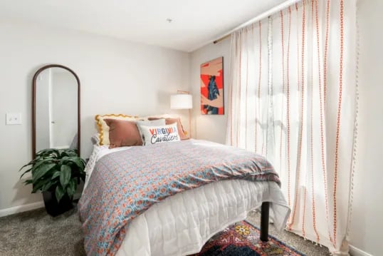 Bed with pillows rug mirror and plant bedroom at Grandmarc at The Corner in Charlottesville Student Accommodation