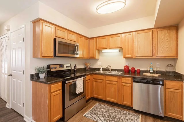 Wooden cabinets stainless steel appliances patterned rug kitchen at Oxford West Apartments in Oxford Student Accommodation