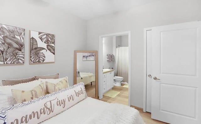 Bed with artwork mirror and bathroom entrance bedroom at Greene Crossing in Columbia Student Accommodation