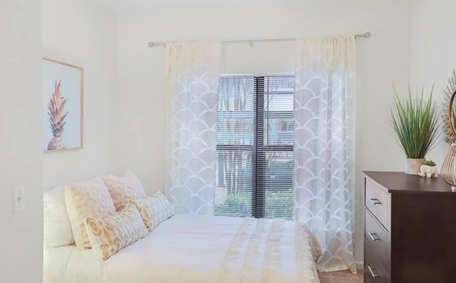 Bed with pillows pineapple art dresser with plants bedroom at Greene crossing flats in Columbia Student Accommodation