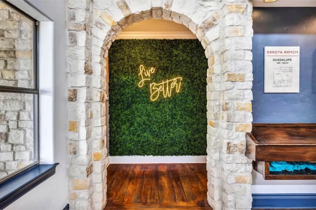 Green wall neon sign and wooden floor hallway at The Ranch Student Apartments in San Marcos Student Accommodation
