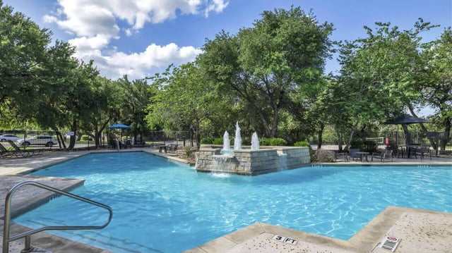 Pool with fountain lounge chairs and tables exterior at The Ranch Student Apartments in San Marcos Student Accommodation