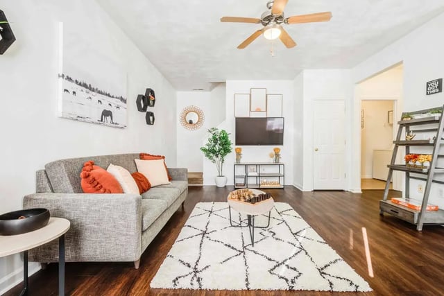 Gray sofa with orange pillows living room at Maple Ridge Townhomes in Blacksburg Student Accommodation