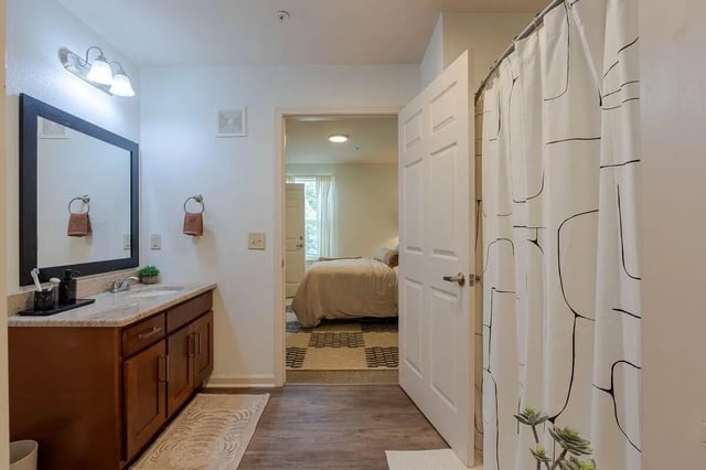 Bathroom vanity mirror towels shower curtain bedroom beyond Bathroom at The View Apartments in State College Student Accommodation