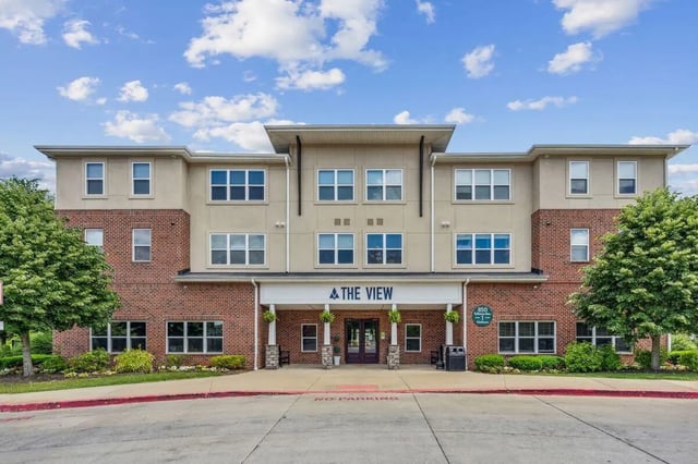 Brick and tan building entrance with trees exterior at The View Apartments in State College Student Accommodation